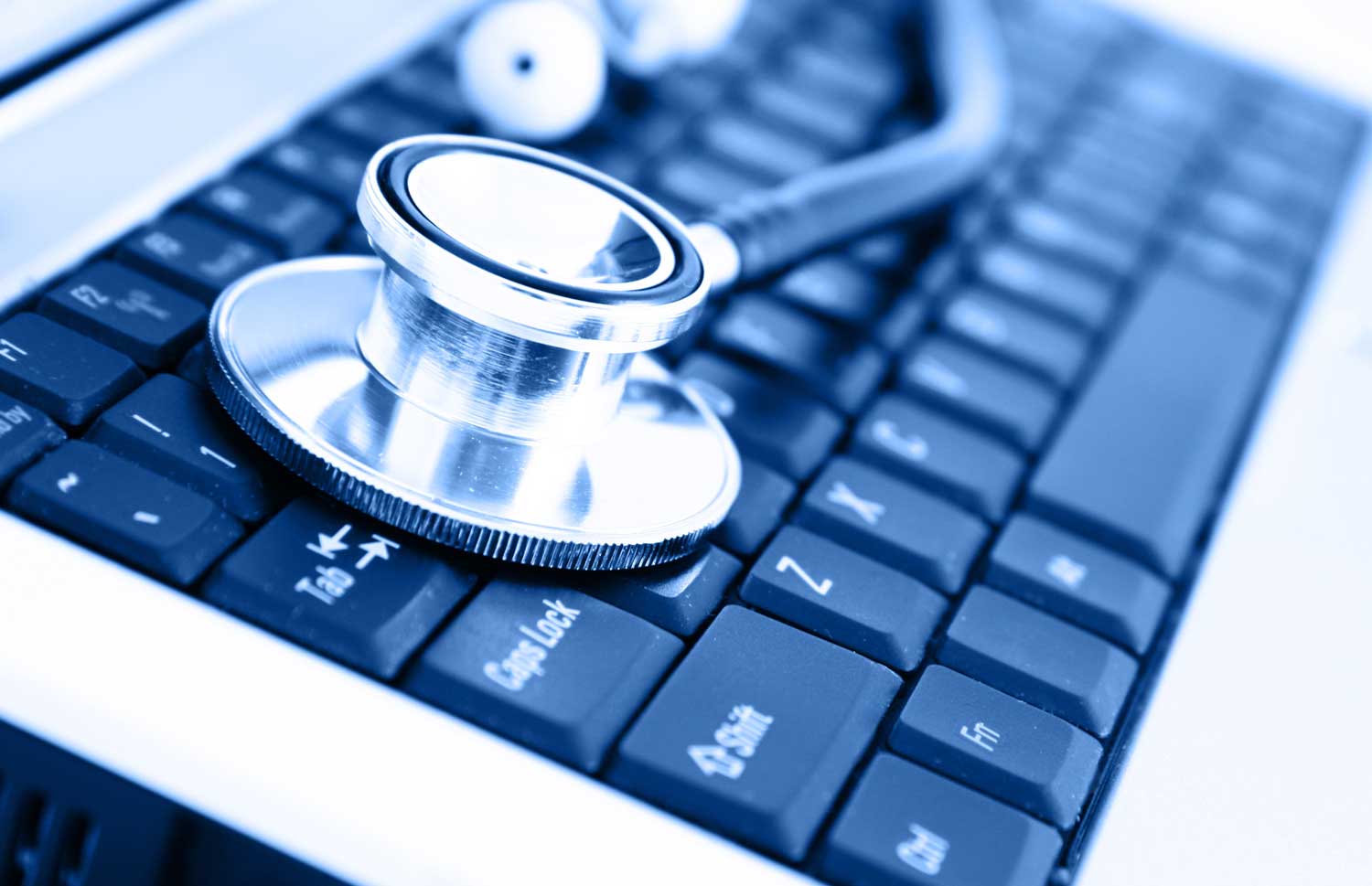 silver and black stethoscope resting on a black computer keyboard