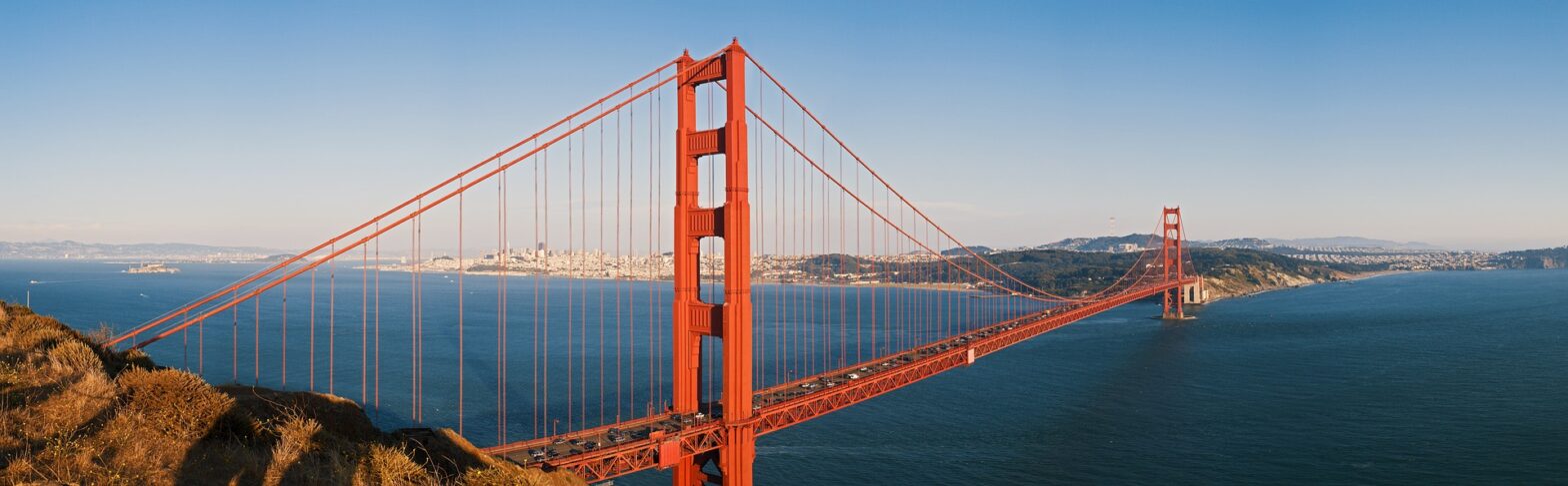 Golden gate bridge with city in background and blue ocean surrounding it