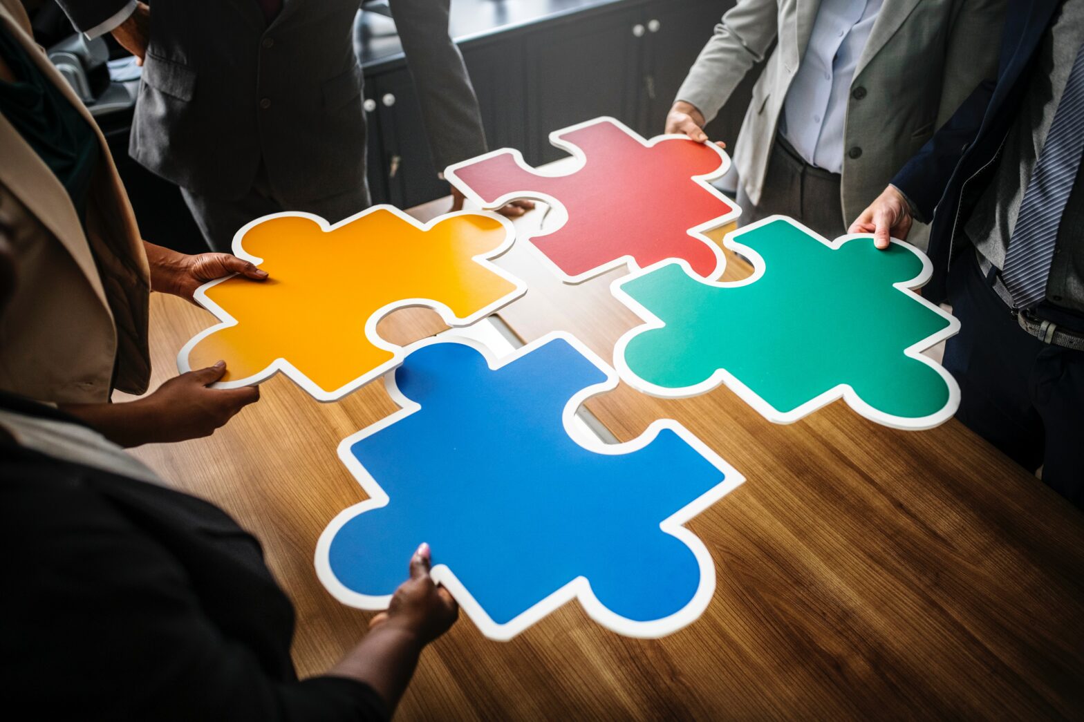 hands putting together large red orange blue and green puzzle pieces