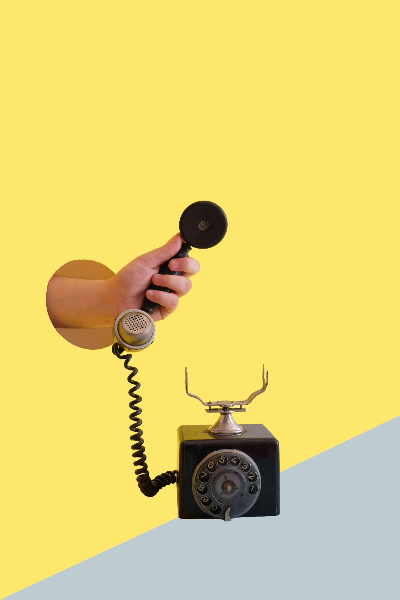 yellow and grey background with old time phone and hand reaching through the wall holding receiver