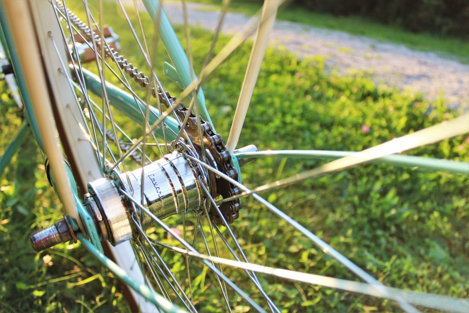 aqua blue bicycle frame with close up of wheel, spokes and chain