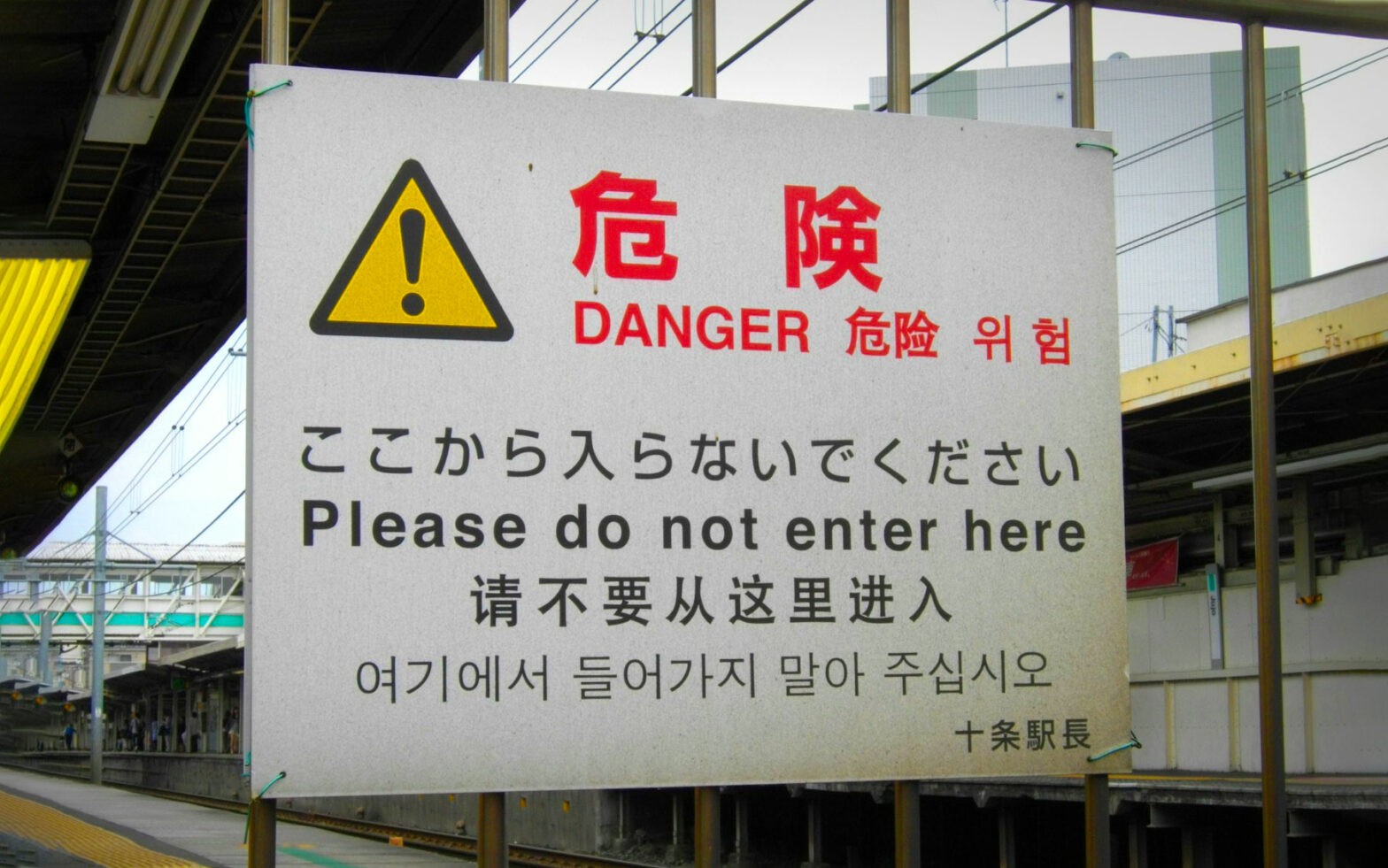 Chinese writing on a white sign in industrial area with red danger letters