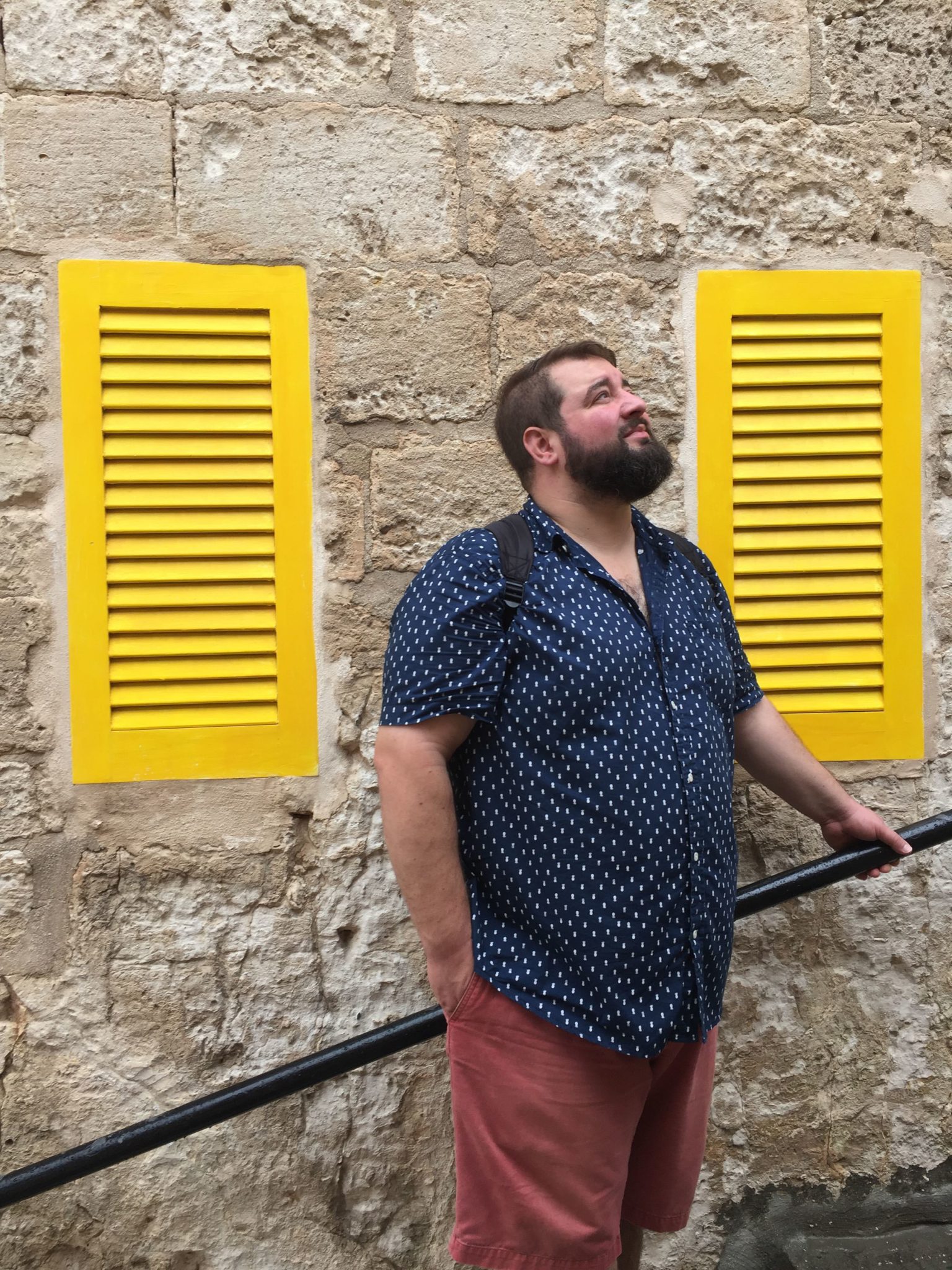 Neil Horowski looking off into distance with yellow shades, stone wall background