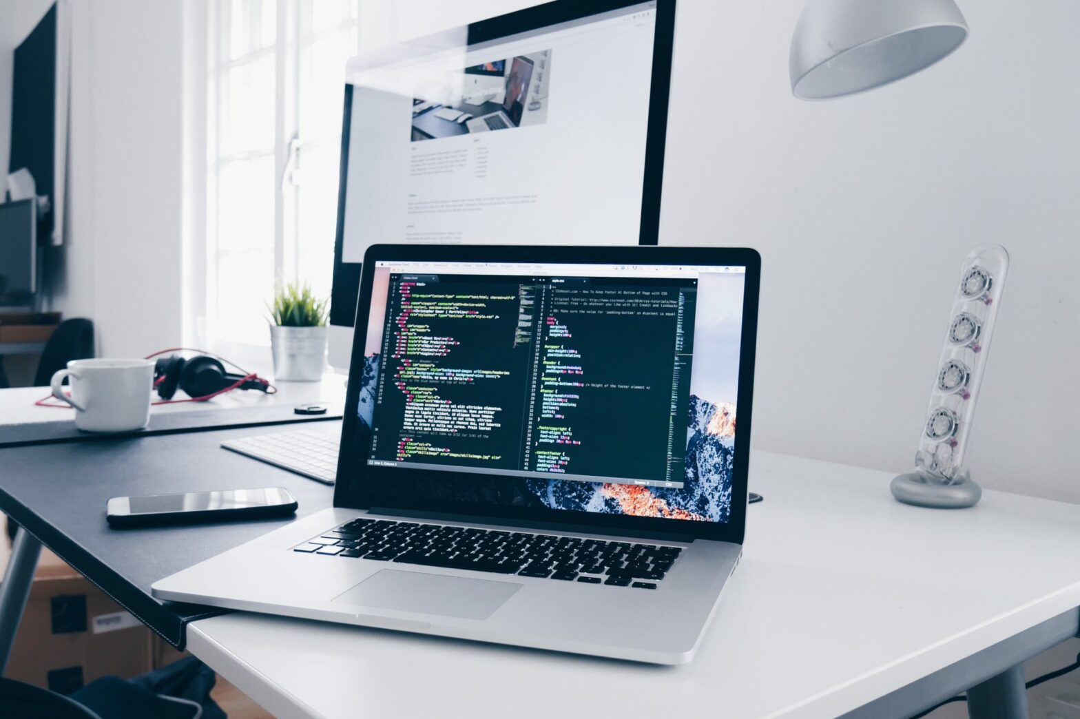 White organized desk with code displayed on Mac computer